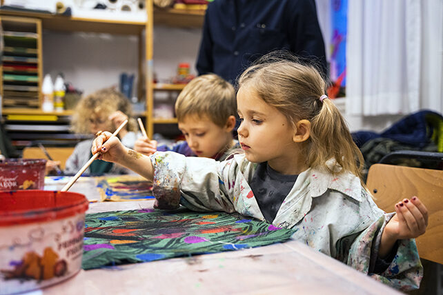 Barn målar på tyger i Skapande verkstaden.