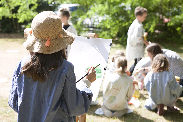Skapande i parken. Ett barn målar med staffli.