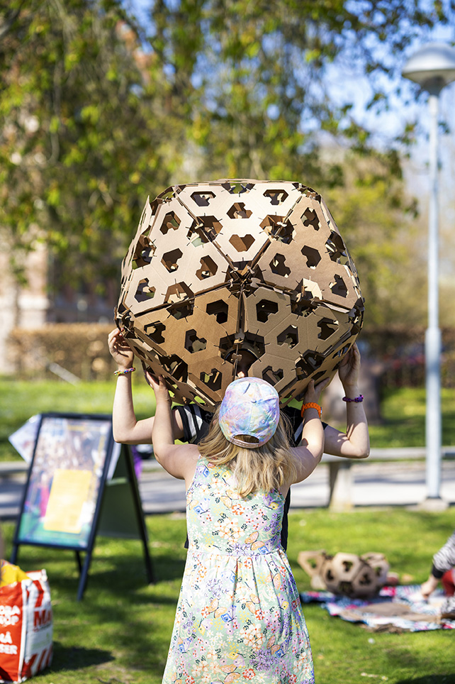 Ett barn lyfter en boll gjord av pappersmoduler.
