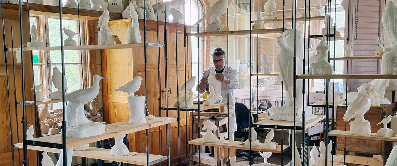 Fredrik Strid arbetar i sin ateljé omgiven av vita fåglar av stearin.