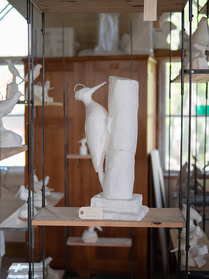 Fågelskulptur i vit stearin står i en hylla.