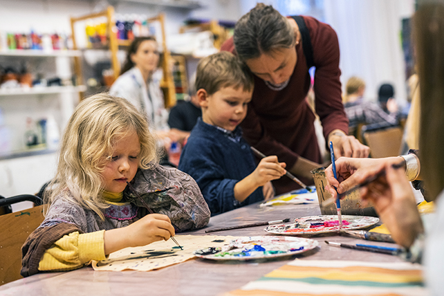 Barn i skapande verkstaden målar med färg på textil.