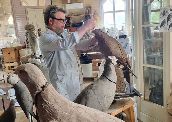Fredrik Strid i sin ateljé. Han skulpterar en stor fågel i lera.