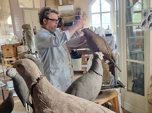 Fredrik Strid i sin ateljé. Han skulpterar en stor fågel i lera.