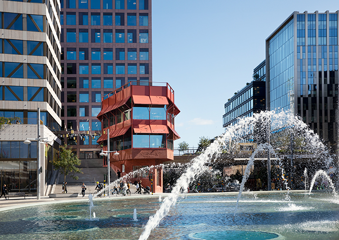 Den röda Sergelpaviljongen vid Sergels torg i Stockholm. I förgrunden en fontän som sprutar vatten.