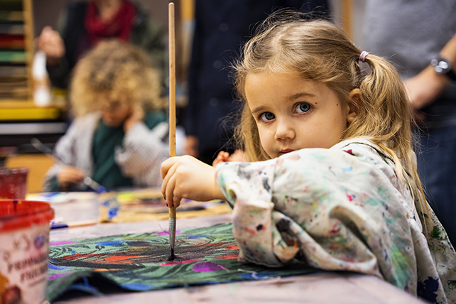 Barn i Skapande verkstaden med pensel i handen.