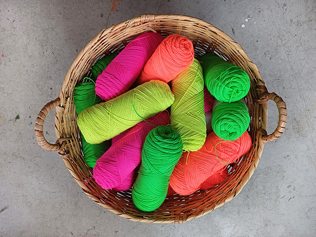 Färgstarka garnnystan i neonfärger ligger i en korg.