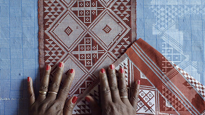 Stillbild från video. Vävar i blått och rött med mönster, händer, digitalt mönster.