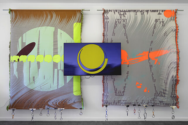 Triptyk, två vävar hänger på en vägg , mellan dem en video.