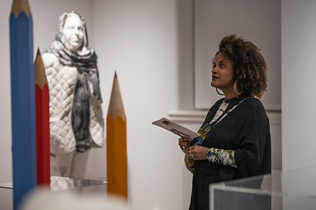 En kvinna tittar på konst. I bakgrunden en skulptur föreställande en kvinna.