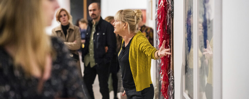 En värd håller visning i en utställning. Gestikulerar med armarna.