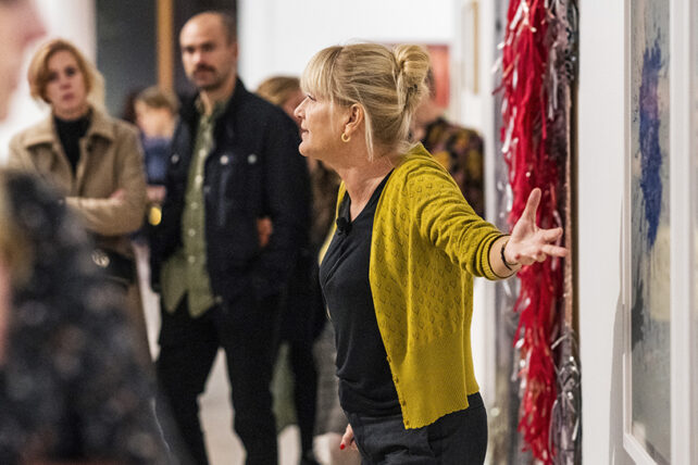 En värd håller visning i en utställning. Gestikulerar med armarna.