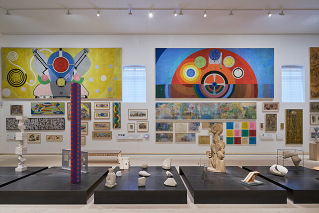 Internationella salen på Skissernas Museum, låga podier med skulpturer, i bakgrunden flera målningar på en vägg.