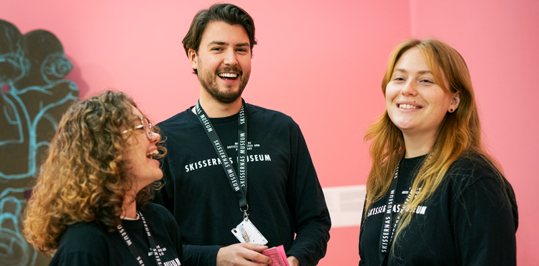 Tre musievärdar pratar med varandra och skrattar.